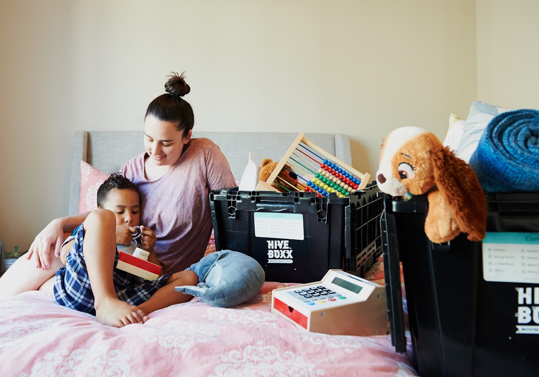 girl-in-pink-shirt-sitting-on-bed-beside-brown-teddy-bear-yjakmaul-c